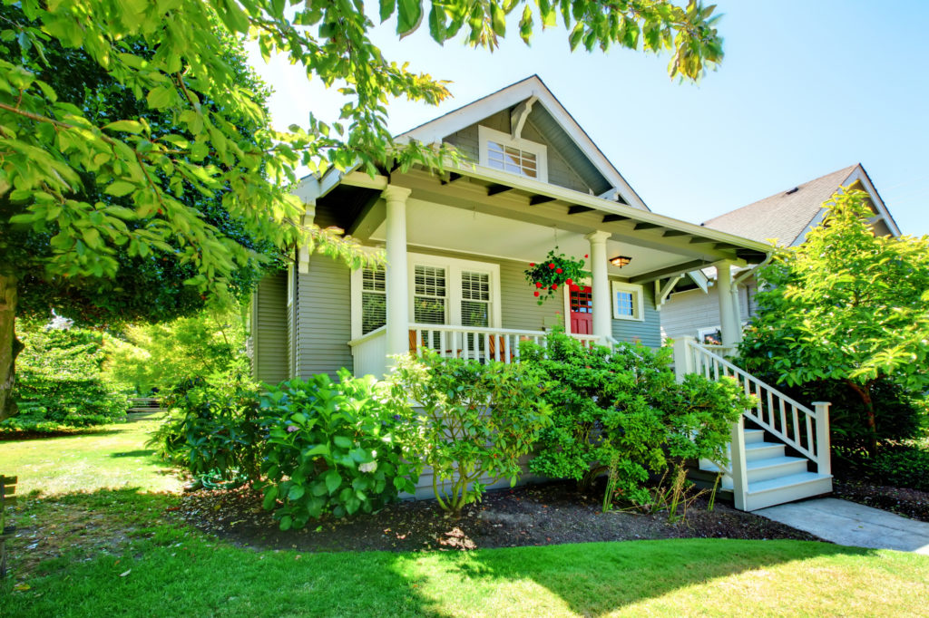 Grey small house with porch and white railings.